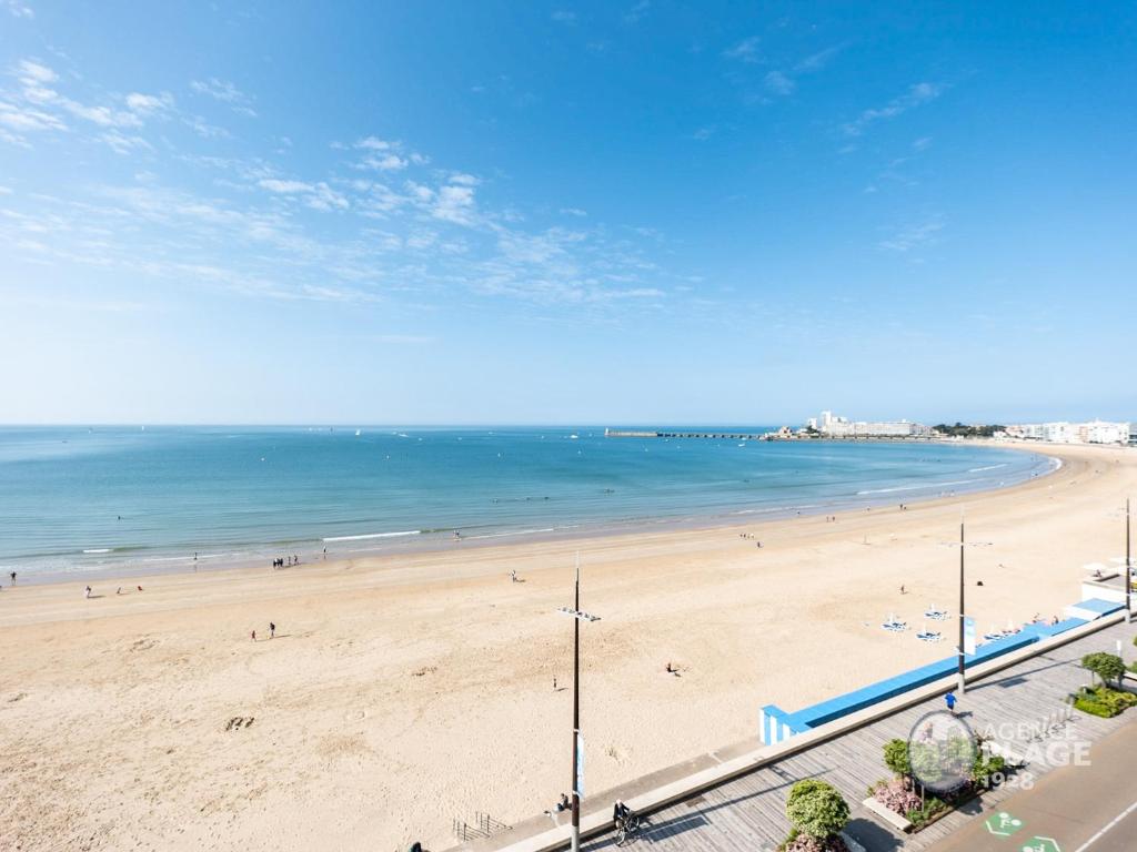 une vue d'une plage avec des gens dans l'eau dans l'établissement Appartement moderne 80m² avec wifi, lave-vaisselle, balcon et vue mer - FR-1-197-539, à Les Sables-dʼOlonne