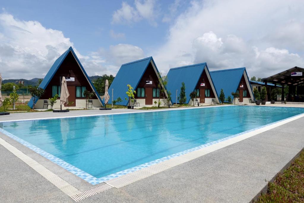 a pool at a resort with blue roofs at SENTA Adventure Camp & Resort in Kampong Minyak Beku