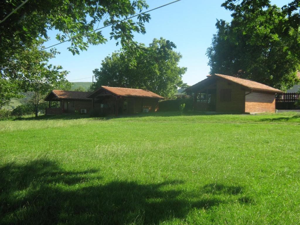un champ d’herbe avec deux bâtiments en arrière-plan dans l'établissement Chalets Etchemendigaraya, à Suhescun