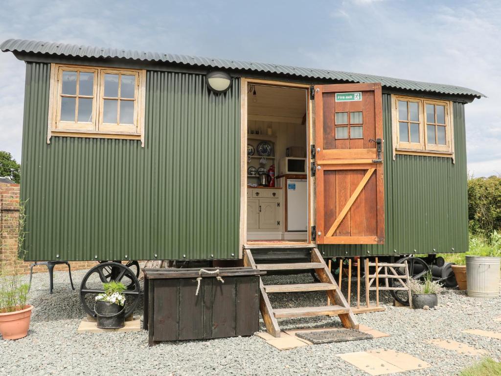a green tiny house with a ladder and a door at Shepherds Hut in Lewes