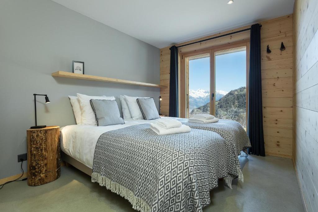 a bedroom with a bed and a large window at Chalet Aramis in La Tzoumaz