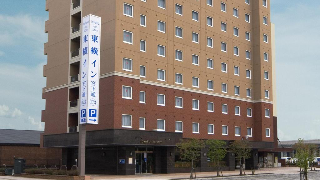 wysoki budynek z znakiem przed nim w obiekcie Toyoko Inn Hokkaido Asahikawa eki Higashi guchi w mieście Asahikawa