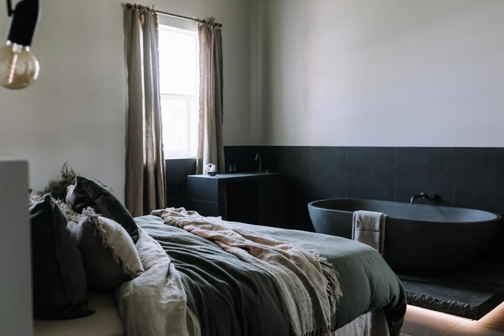 Schlafzimmer mit einem Bett und einer Badewanne in der Unterkunft The Benev - Wellness Accommodation and Spa Beechworth in Beechworth