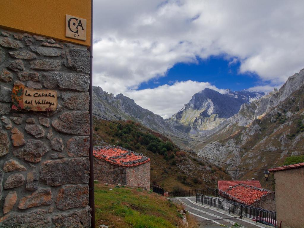 a view of a mountain valley with buildings and a sign at Casa Rural La Cabaña del Valleyu in Sotres