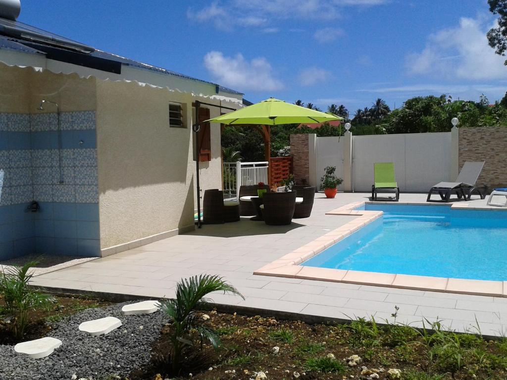 - une piscine avec un parasol à côté d'une maison dans l'établissement LE PLAISIR, au Gosier
