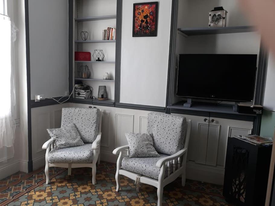 a living room with two chairs and a flat screen tv at Maison de ville proche beauval avec parking in Selles-sur-Cher