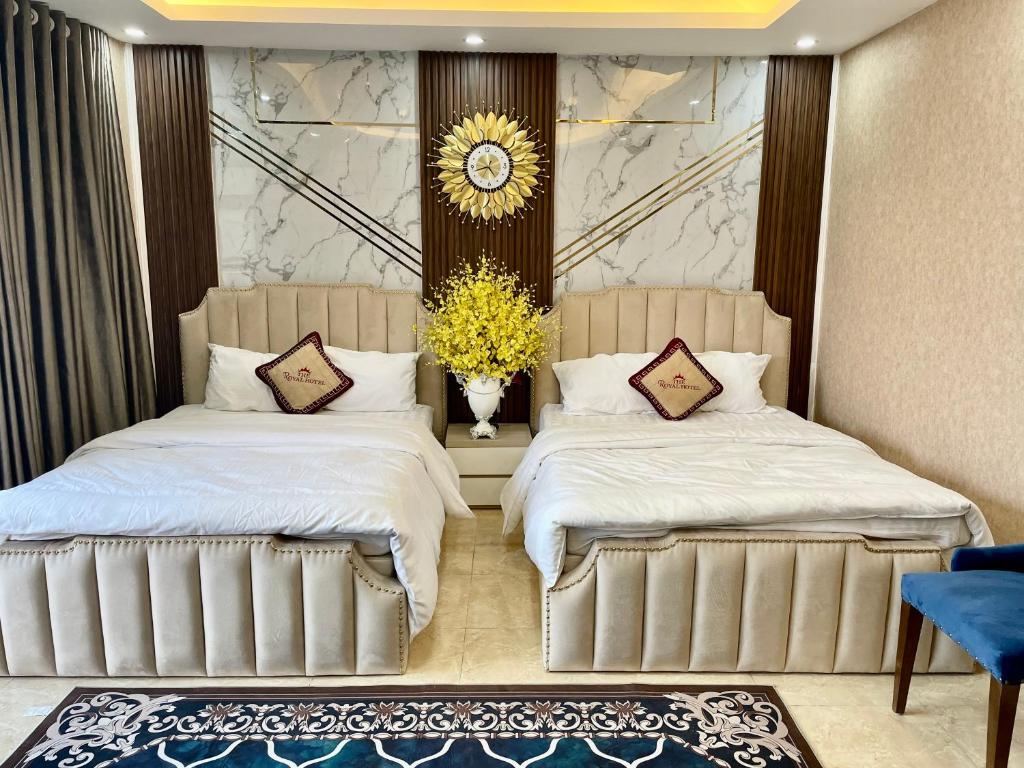 um quarto com duas camas e um vaso de flores em The Royal Hotel Near West Lake em Hanói