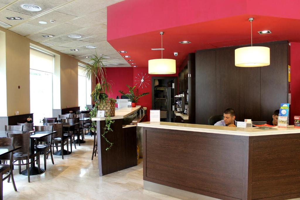 a restaurant with a woman sitting at a counter at Hotel Coronado in Barcelona