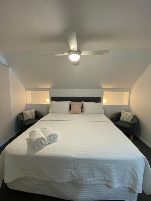 Un dormitorio con una cama blanca con toallas. en Rainbow Beach Dream Studio Motel Style Apartment en Rainbow Beach