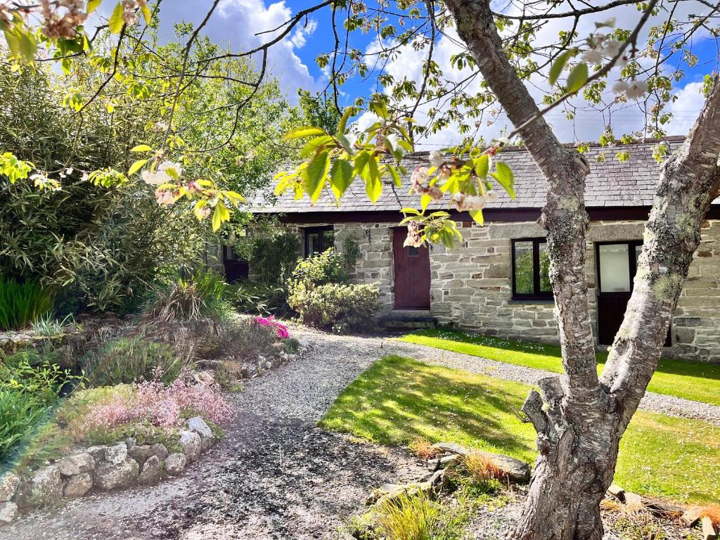 a stone house with a tree in front of it at Swift Cottage in Liskeard