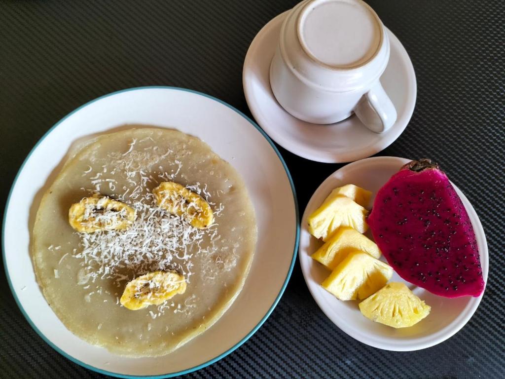 Una mesa con dos platos de comida y una taza de café. en Ojek's Homestay, en Ubud