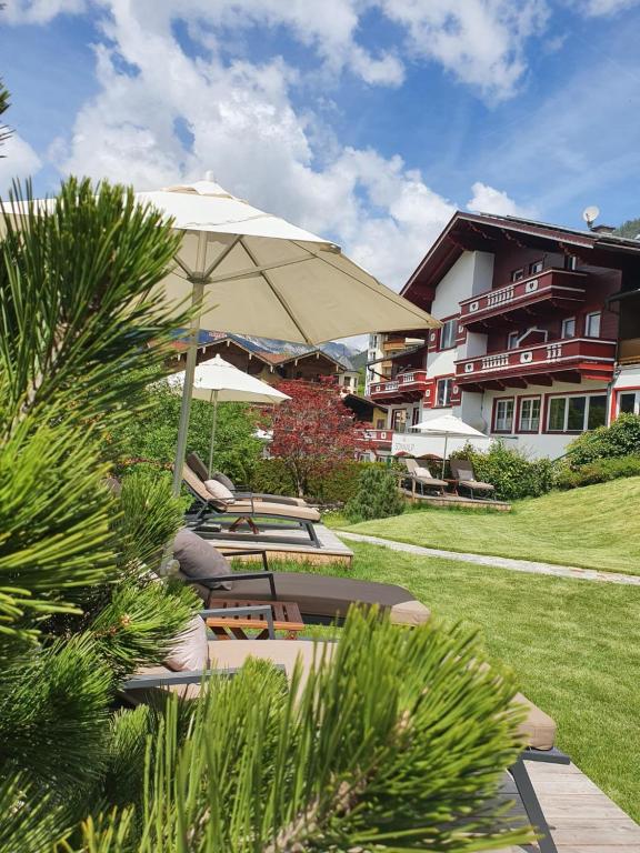 eine Terrasse mit Stühlen, einem Sonnenschirm und einem Gebäude in der Unterkunft Garni Das SONNALP in Maurach