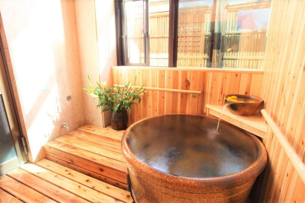 a bath tub in a wooden room with a window at Sakadojo in Minami Uonuma