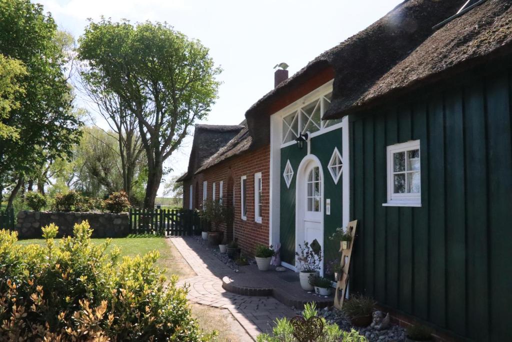 una casa verde con techo de paja en Kastanienhof en Tümlauer Koog