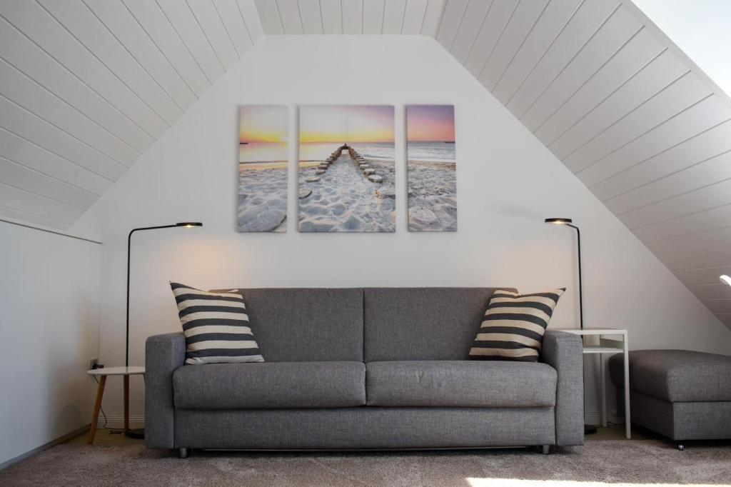 ein Wohnzimmer mit einem Sofa und zwei Gemälden an der Wand in der Unterkunft Wohnung Wattwurm in Norderney