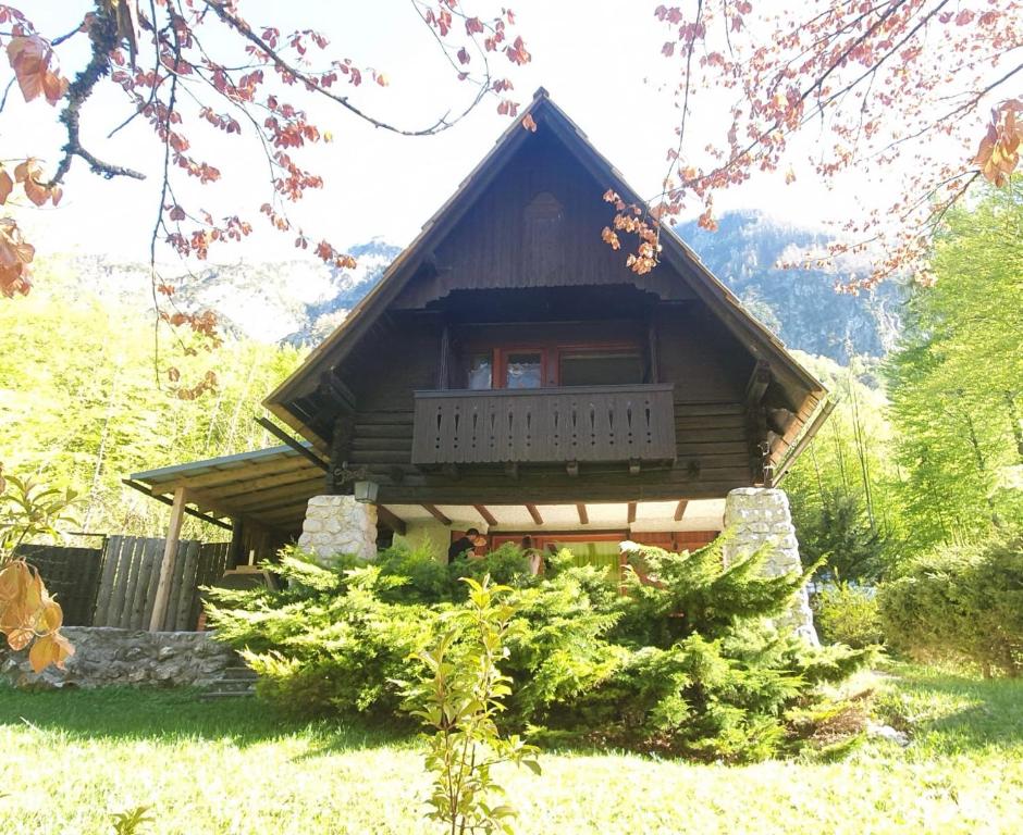 a small log cabin with a balcony in a yard at Red Beech Cabin at Lake Bohinj & Triglav National Park in Bohinj