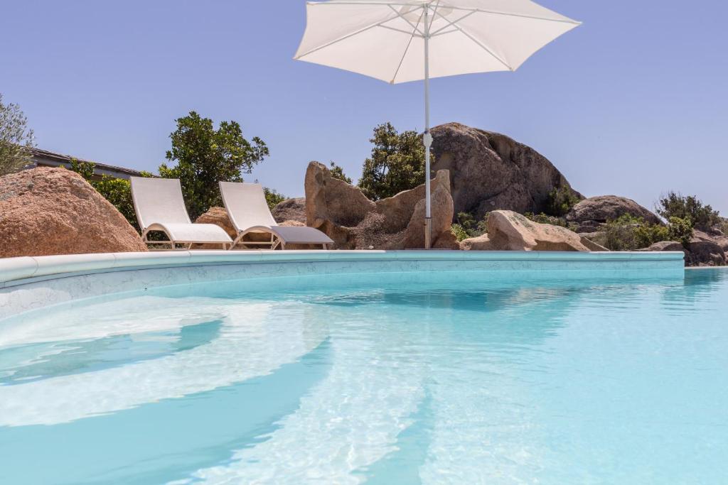 a swimming pool with chairs and an umbrella at villa Le farfalle in San Teodoro