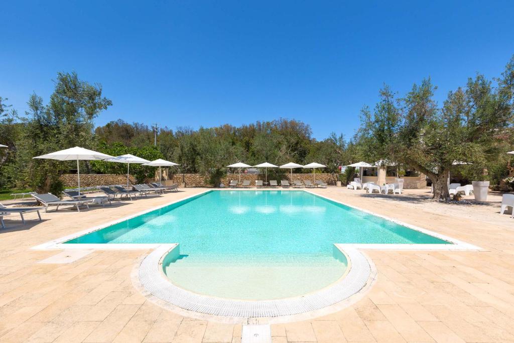 una gran piscina con sillas y sombrillas en Masseria San Biagio, en Calimera