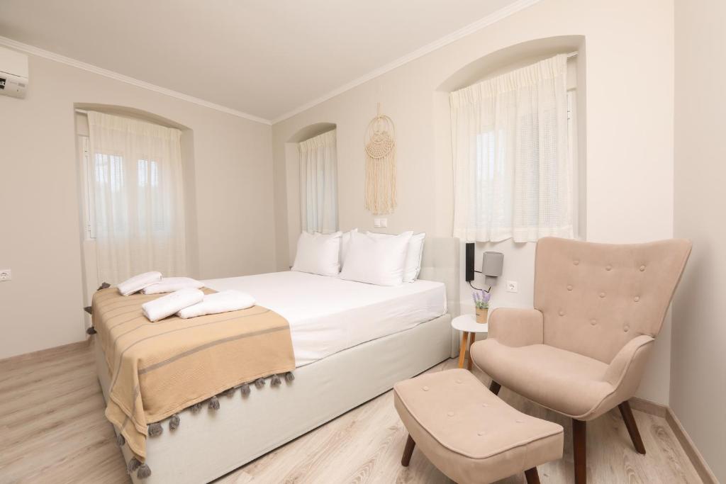 a white bedroom with a bed and a chair at F&T Villa in Corfu Town