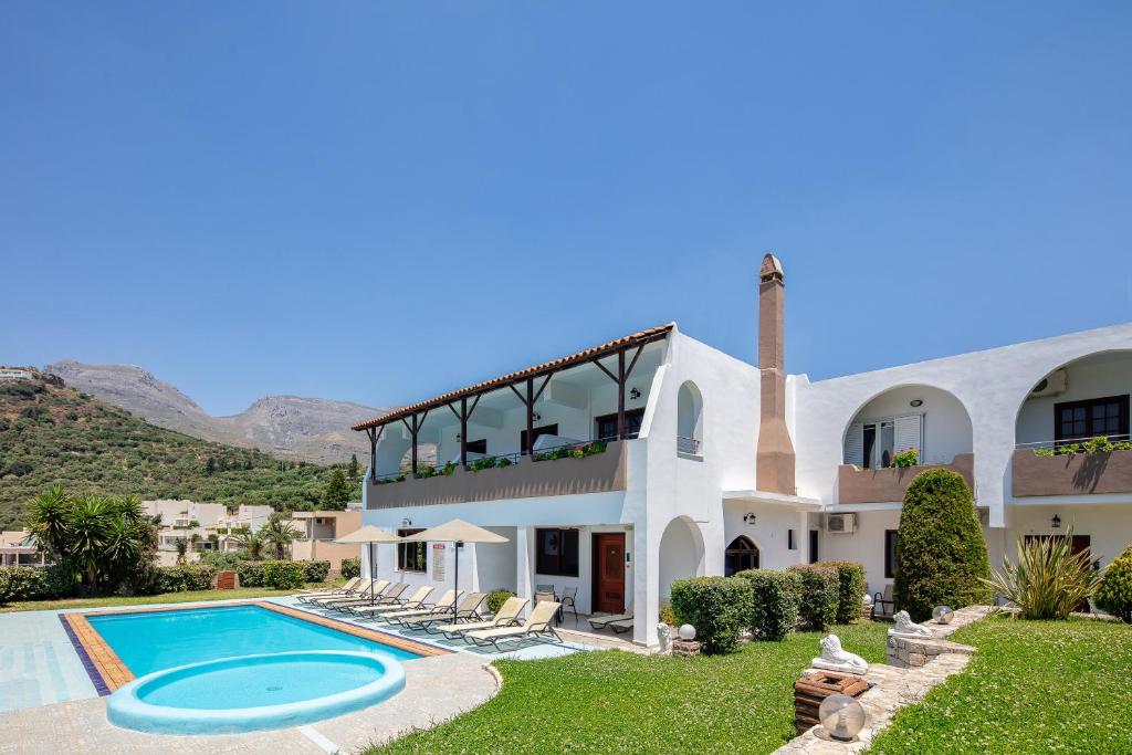 a large white house with a swimming pool at Anthos Apartments in Plakias