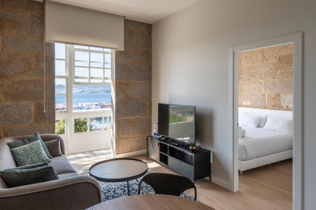 een slaapkamer met een bed en een woonkamer met een tv bij Bow Homes by Como en Casa in Vigo