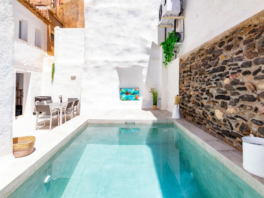 una piscina en una casa con una pared de piedra en Casa La Alberquilla, en Nigüelas