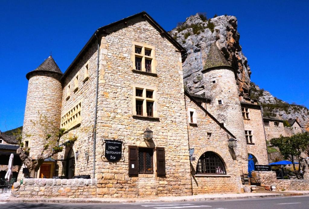 un edificio de piedra con dos torres en una montaña en Hôtel-Restaurant Le Manoir De Montesquiou en La Malène
