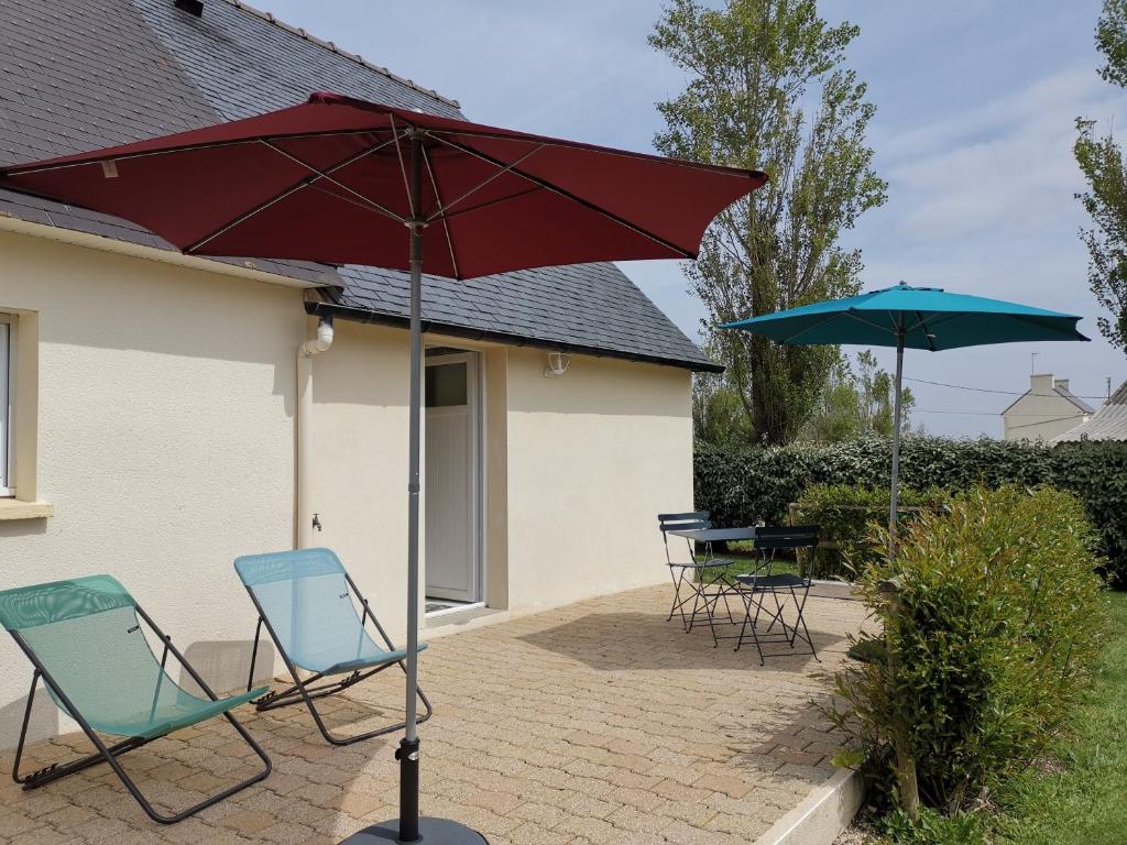 een patio met 2 stoelen en een rode parasol bij Ty Bian, à la campagne et proche de la plage in Le Conquet
