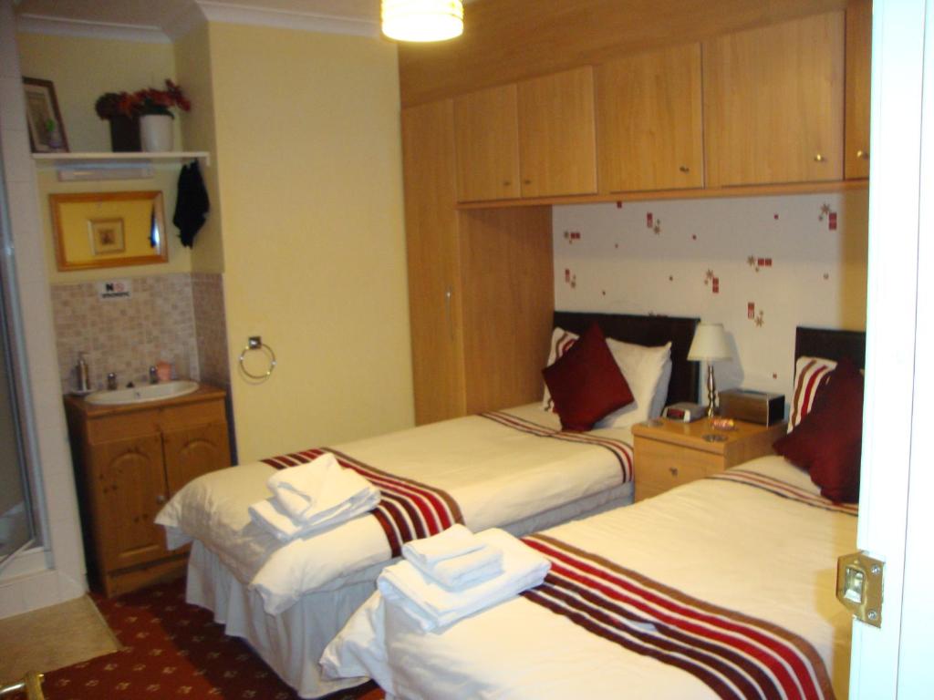 a hotel room with three beds with towels on them at Ashgrove Bed and Breakfast in Kirkcaldy