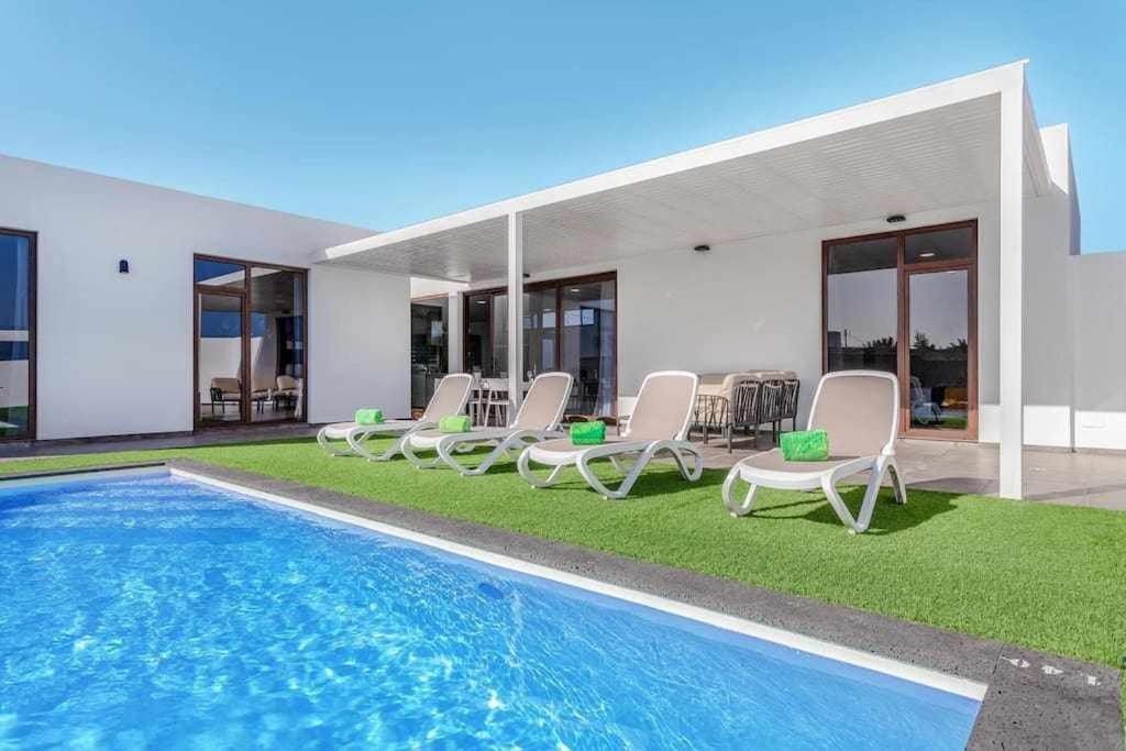 a swimming pool with chairs and a house at Villa Ponzos Chalet independiente y privado in Triquivijate