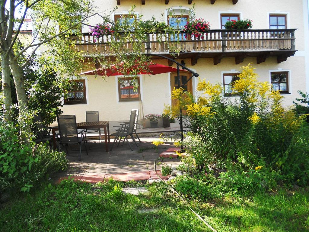 ein Haus mit einer Terrasse mit einem Tisch und einem Balkon in der Unterkunft Ferienhaus am Waginger See in Kirchanschöring