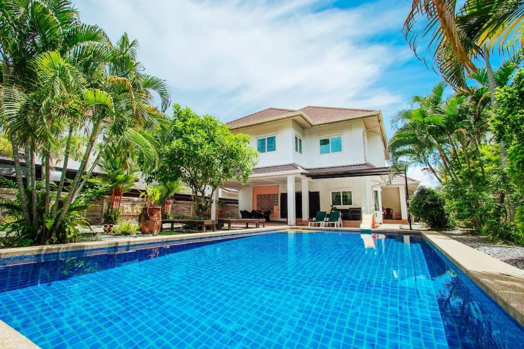 a villa with a swimming pool in front of a house at PRIVATE RESIDENCE HOSTED by Sasithorn in Nong Prue