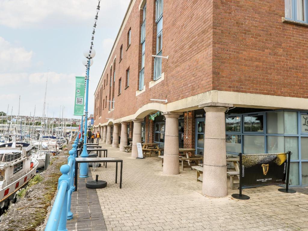 a building next to a marina with tables and boats at 15 Sovereign House in Milford Haven