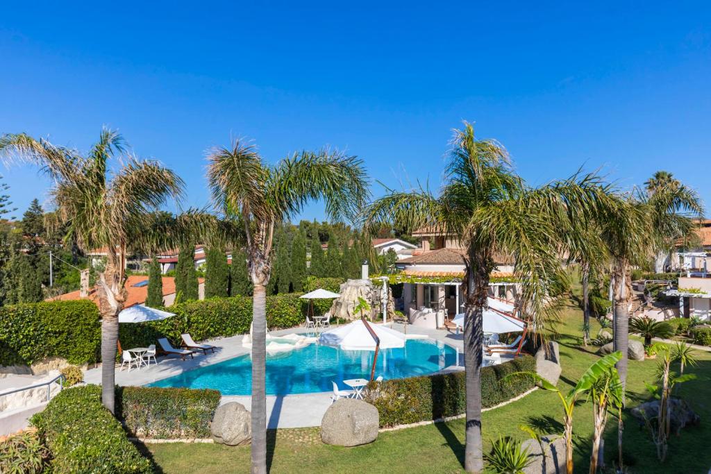 - une vue aérienne sur la piscine du complexe bordée de palmiers dans l'établissement L' Arcobaleno Resort, à Capo Vaticano