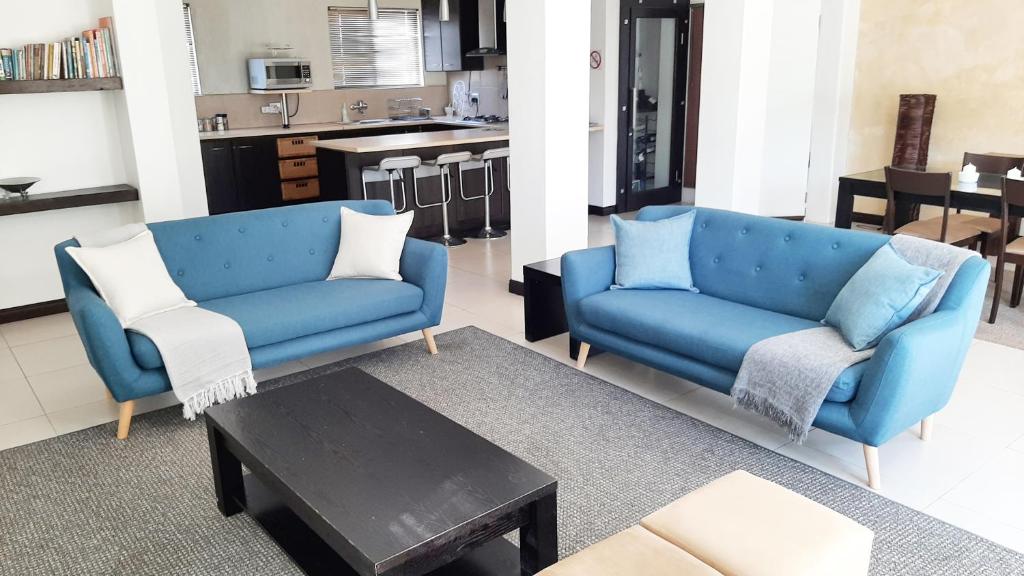 a living room with a blue couch and a table at Hadingham Russell Holiday House in Hermanus