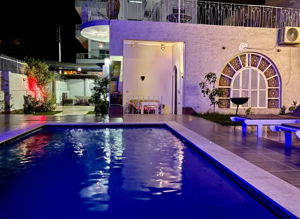 a swimming pool in front of a building with a house at Luxor Oasis Guest House in Luxor