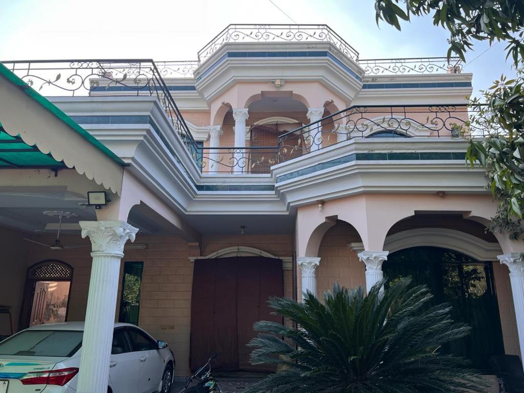 a pink house with a car parked in front of it at Amira Villa 1 Kanal 5 bedroom house, Johar Town Lahore in Lahore