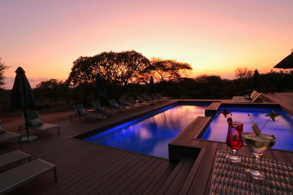 a swimming pool with a sunset in the background at Tshukudu Game Lodge in Hoedspruit