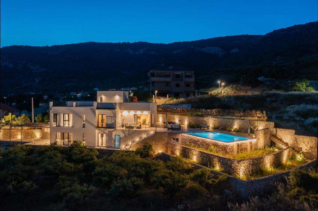 - une vue aérienne sur une villa avec une piscine la nuit dans l'établissement Luxury Villa Envivo Komiža with heated pool and professional gym, à Komiža