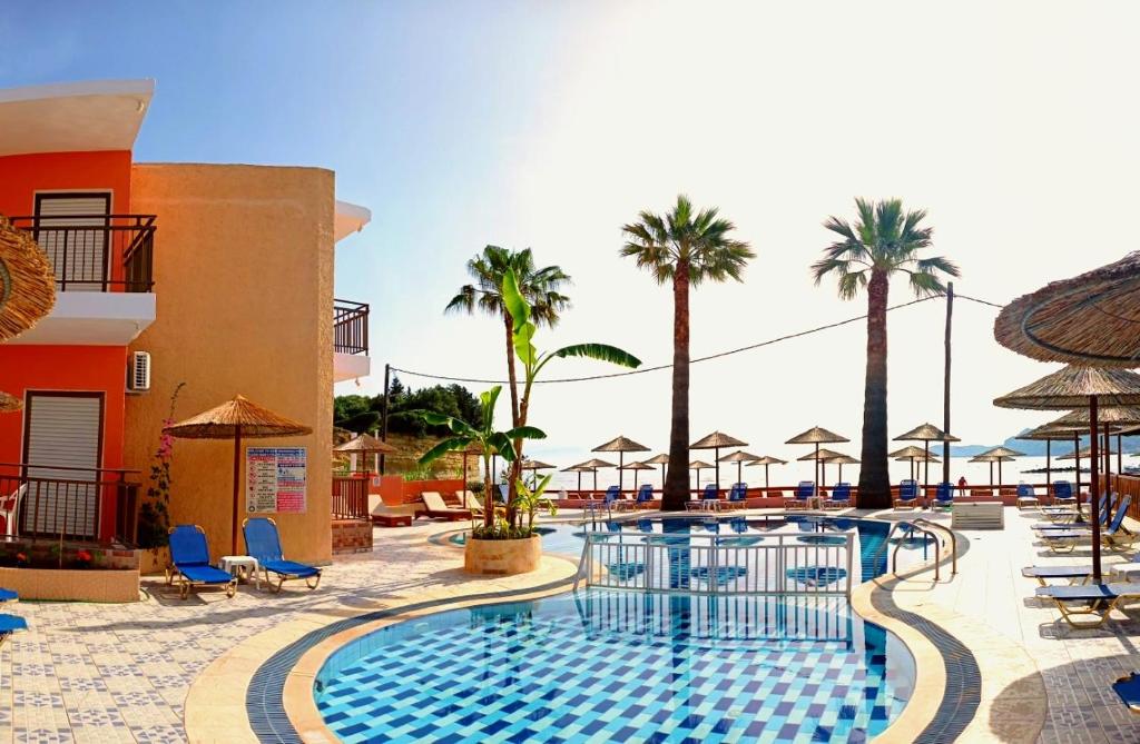 シダリにあるMaria's Beach Apartmentsのヤシの木と傘が備わるリゾートのプールを利用できます。