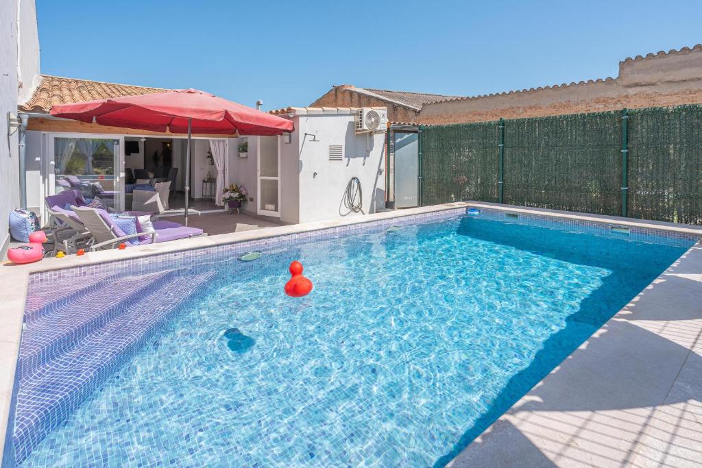 uma grande piscina com um guarda-sol vermelho e uma lata em Ca sa Tia em Binissalem