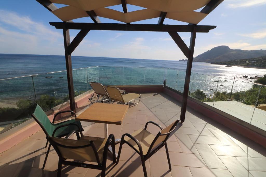 a balcony with a table and chairs and the ocean at Horizon Beach Hotel in Plakias