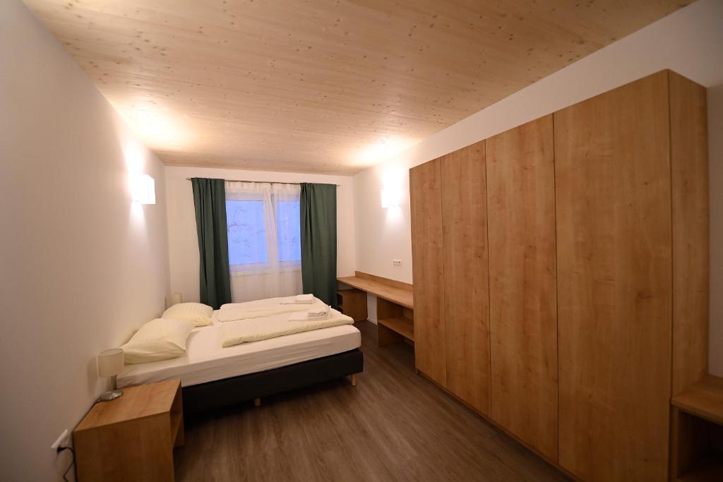 a bedroom with a bed and a large wooden cabinet at Campus Ferlach in Ferlach