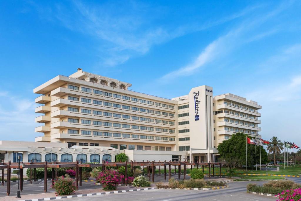 a large white building in front of a parking lot at Radisson Blu Hotel & Resort, Al Ain in Al Ain