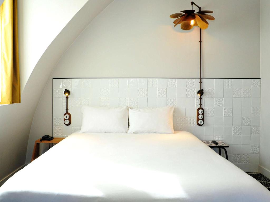 a white bed with two pillows and a ceiling fan at ibis Styles Paris Gare De Lyon TGV in Paris