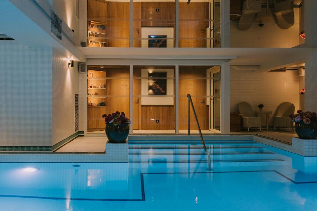 a swimming pool in a building with a house at Grand Tonic Hotel & SPA NUXE in Biarritz