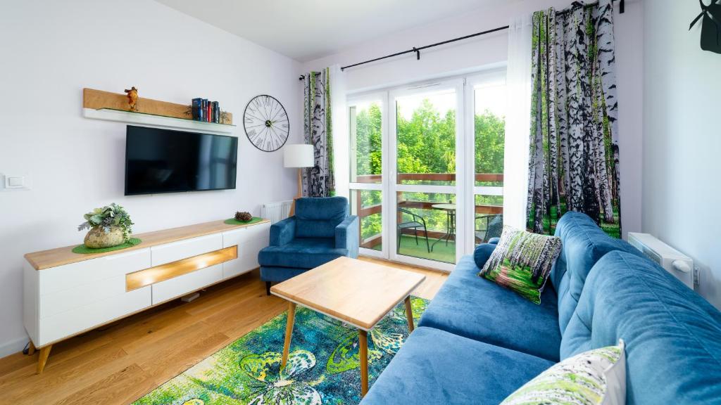 a living room with a blue couch and a tv at Holiday Mountain Residence, Sun & Snow in Świeradów-Zdrój