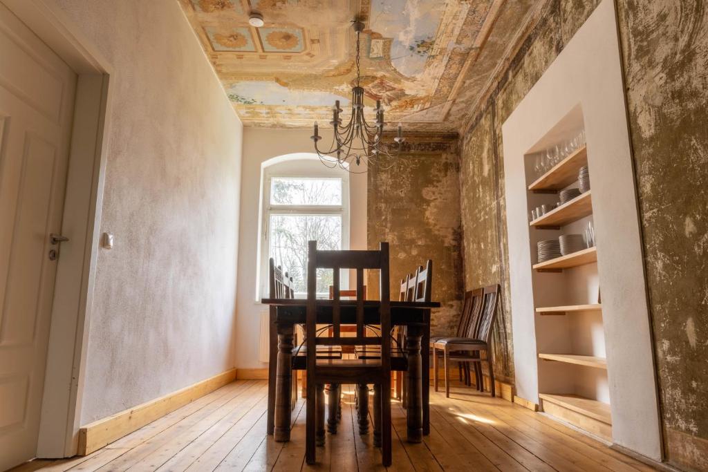 uma sala de jantar com uma mesa e cadeiras e um tecto em Zeitreise: Wohnen im Herrenhaus genau zw. L u. DD em Mügeln