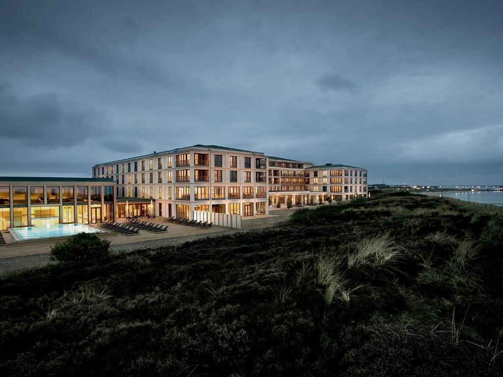 un edificio en una colina junto a un cuerpo de agua en A-ROSA Sylt en List