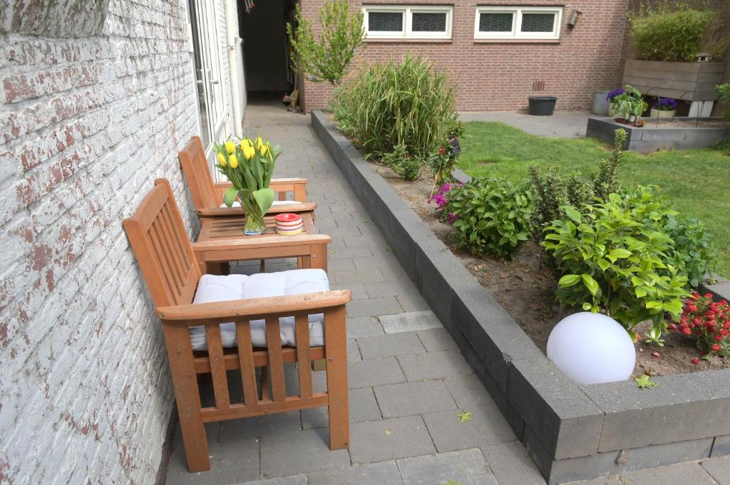 a garden with a bench and a table with flowers at AaBenB appartement in Tilburg